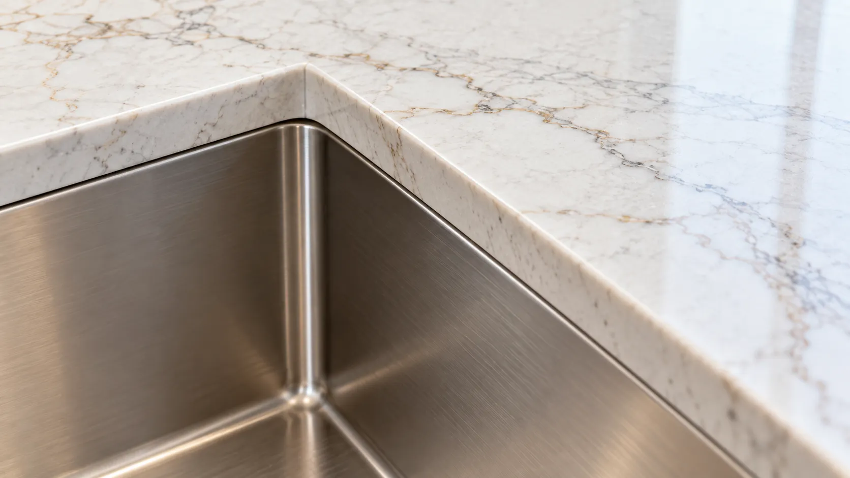 Close detail of a quartz countertop edge meeting an undermount sink bowl, showing the reveal